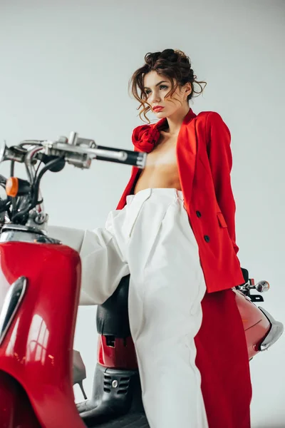 Low angle view of attractive and stylish girl near red motorcycle on white — Stock Photo