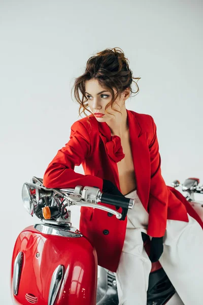 Mujer joven seria y elegante sentada en motocicleta roja en blanco - foto de stock
