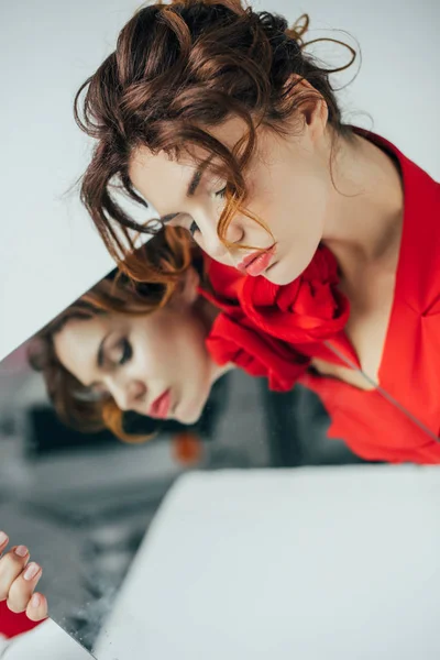 Selective focus of attractive redhead young woman with closed eyes holding mirror on white — Stock Photo