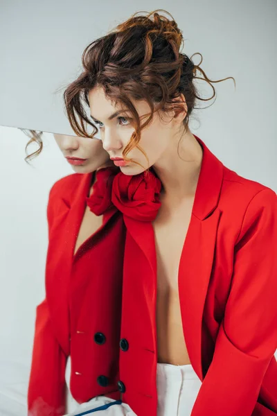 Mujer joven elegante y bonita cerca del espejo en gris - foto de stock