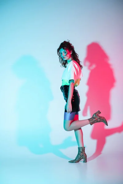 Attraktive und stylische lockige junge Frau steht auf blau mit Beleuchtung — Stockfoto