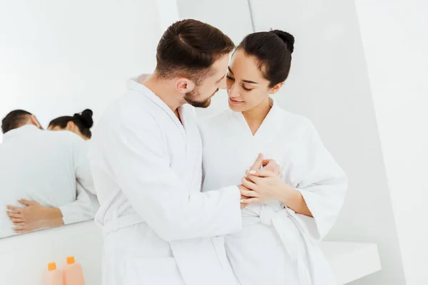 Alegre chica cogida de la mano mientras mira barbudo novio en cuarto de baño - foto de stock