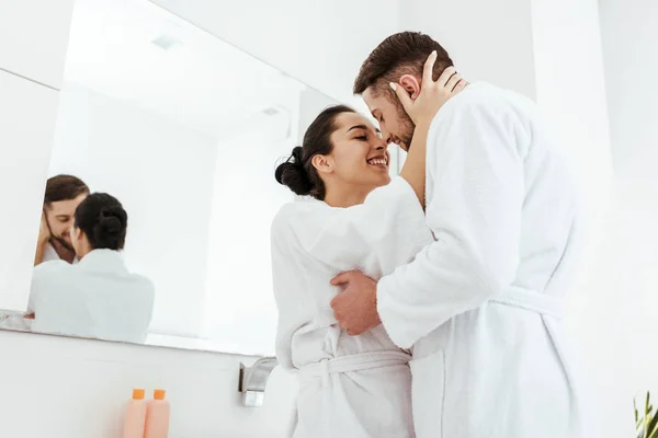 Low angle view of happy girl smiling while hugging boyfriend in bathrobe — Stock Photo