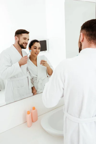 Selective focus of cheerful brunette woman taking photo with happy man holding toothbrush — Stock Photo