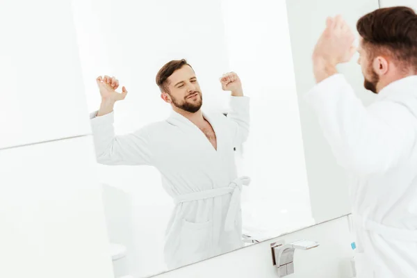 Foco seletivo de homem barbudo feliz alongamento após acordar no banheiro — Fotografia de Stock