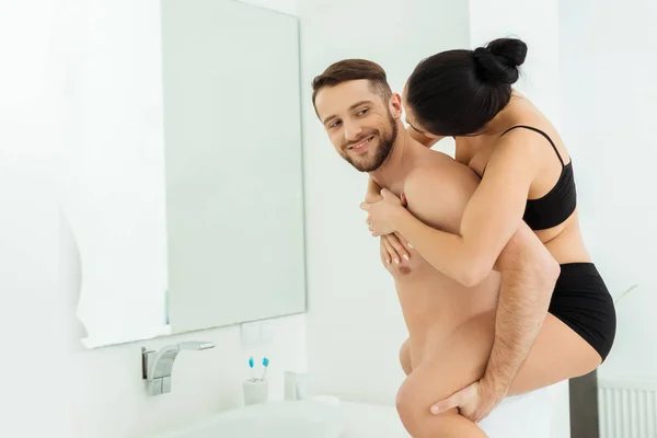 Happy shirtless man piggybacking brunette girlfriend in black underwear — Stock Photo