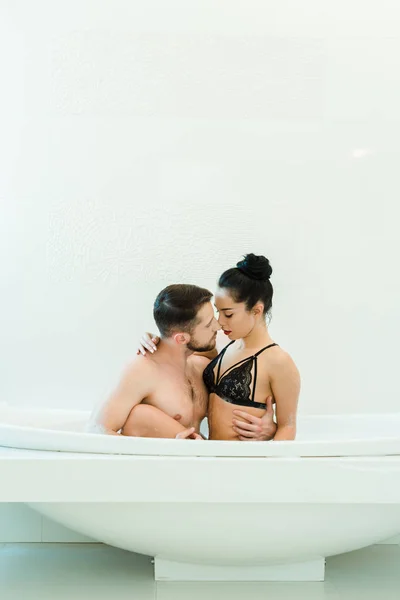 Bel homme torse nu regardant et touchant femme brune sexy en soutien-gorge noir — Photo de stock