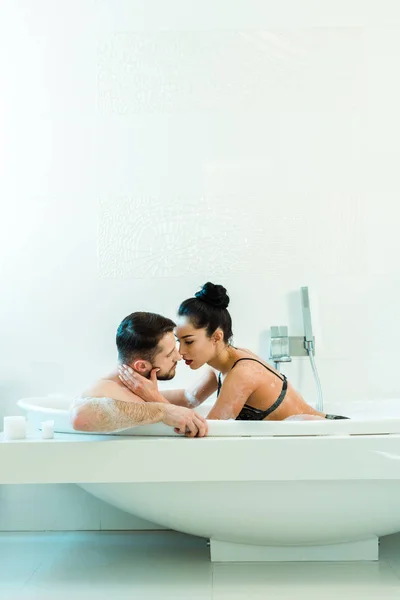 Sexy brunette femme toucher le visage de beau petit ami dans la baignoire — Photo de stock