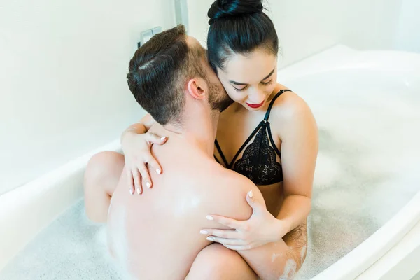 Вид зверху бородатий чоловік цілує шию молодої жінки у ванній — стокове фото
