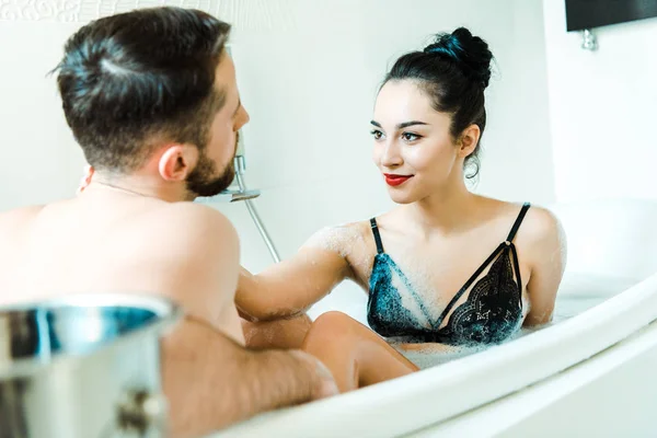 Foyer sélectif de fille heureuse regardant l'homme barbu dans la baignoire — Photo de stock
