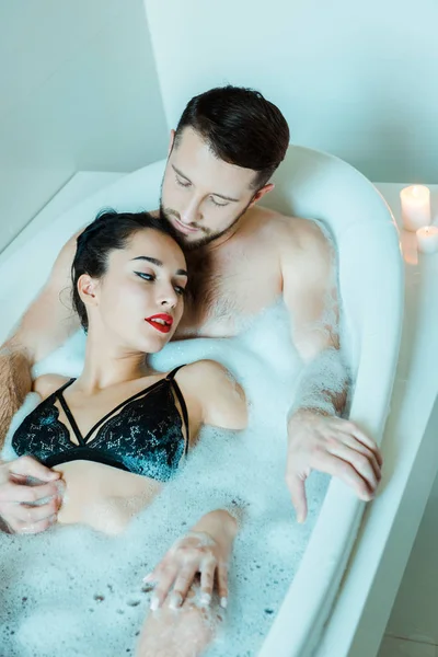 Vue aérienne d'une jolie fille brune couchée avec un homme barbu dans une baignoire — Photo de stock