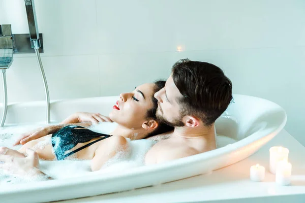 Attrayant brunette jeune femme couché avec barbu homme dans baignoire — Photo de stock
