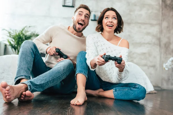 Baixo ângulo de visão de homem feliz e mulher jogando videogame em casa — Fotografia de Stock