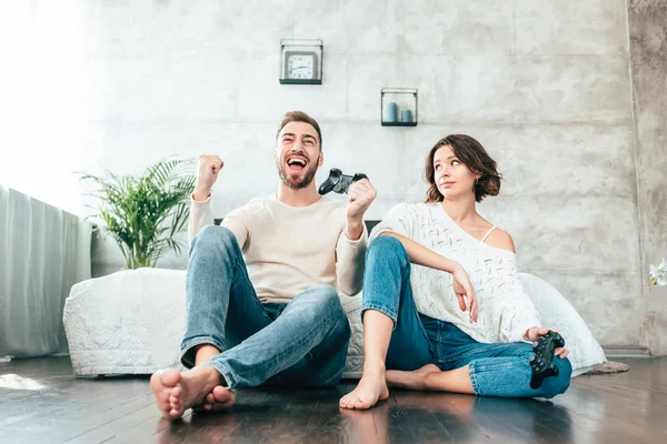 Vista de ángulo bajo de la mujer atractiva mirando al hombre feliz gesto mientras juega videojuego - foto de stock