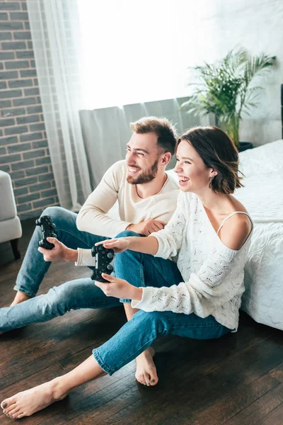 Homme heureux et attrayant femme jouer à un jeu vidéo à la maison — Photo de stock