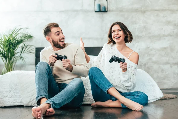 Homem surpreso olhando para mulher alegre jogando videogame em casa — Fotografia de Stock