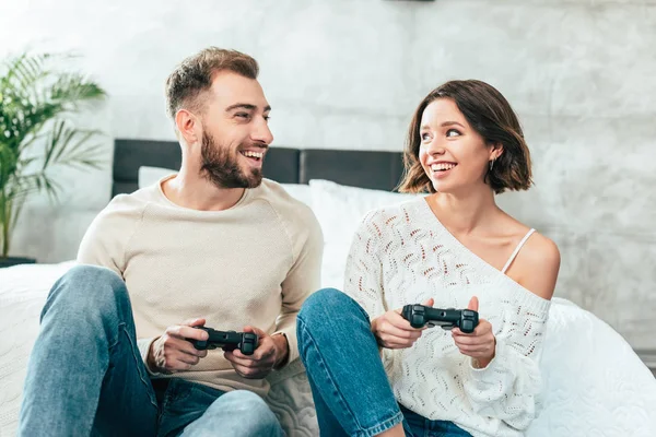 Happy man looking at cheerful woman holding joystick at home — Stock Photo
