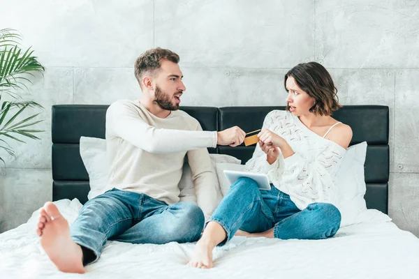 Homem insatisfeito tomando cartão de crédito de mãos de mulher chateada — Fotografia de Stock