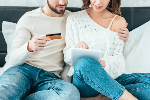 Обрізаний вид чоловіка, який тримає кредитну картку і обіймає жінку з цифровим планшетом — стокове фото