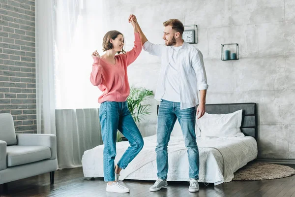 Brünette Frau tanzt mit gutaussehendem bärtigen Mann im Schlafzimmer — Stockfoto