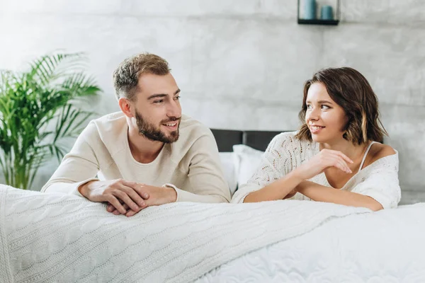 Glücklicher Mann und attraktive Frau schauen einander im Schlafzimmer an — Stockfoto