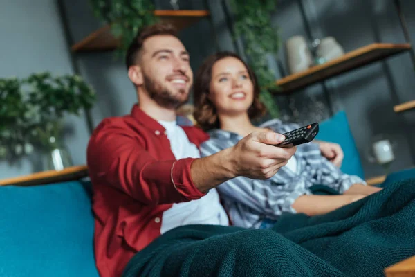 Enfoque selectivo de hombre feliz sosteniendo el mando a distancia mientras ve la película con la mujer - foto de stock