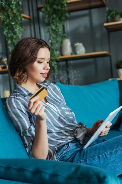 Femme attrayante regardant tablette numérique tout en tenant la carte de crédit — Photo de stock