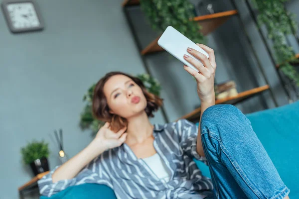 Enfoque selectivo de la mujer con cara de pato tomando selfie en casa - foto de stock