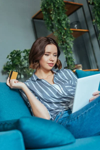 Niedrigwinkel-Ansicht der schönen Frau, die auf digitales Tablet schaut, während sie Kreditkarte hält — Stockfoto