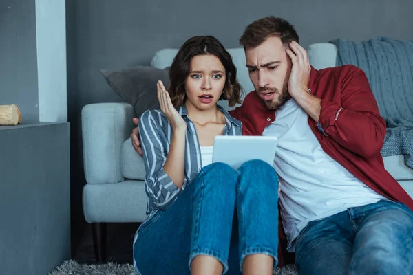 Shocked man and woman gesturing while watching video on digital tablet — Stock Photo