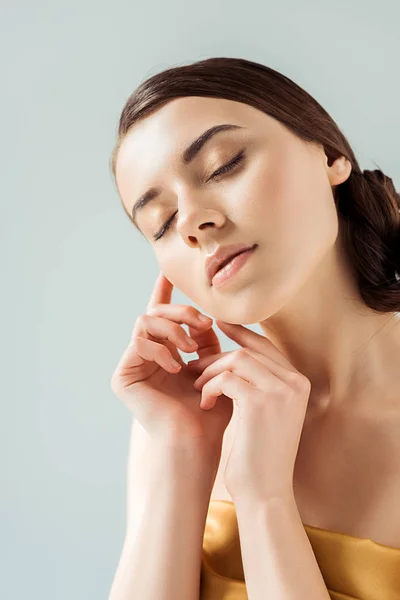 Young woman with closed eyes, shiny lips and golden eye shadow isolated on grey — Stock Photo