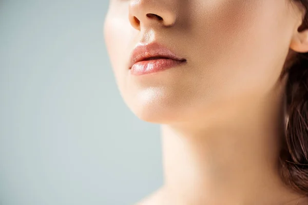 Обрізаний вид молодої жінки з блискучими губами на сірому фоні — стокове фото