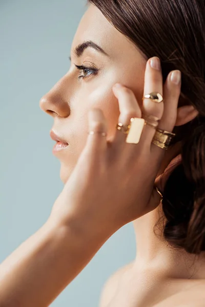 Профиль молодой женщины с золотыми кольцами, изолированными на сером — стоковое фото