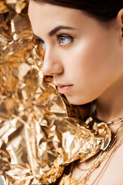 Молода жінка з блискучим макіяжем і золотою фольгою в намистах дивиться — стокове фото