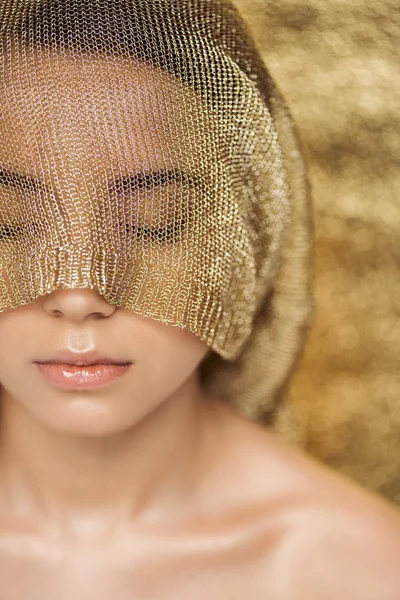 Jeune femme nue avec des lèvres brillantes et tissu doré sur le visage sur fond texturé or — Photo de stock