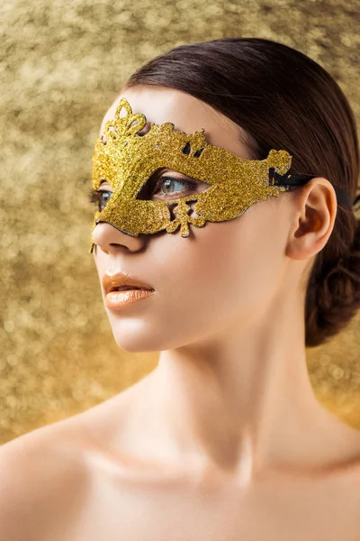 Junge nackte Frau in goldener Maske mit glänzendem Make-up auf texturiertem goldenem Hintergrund — Stockfoto