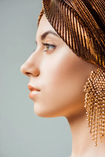 Profile of young woman with shiny make up, turban and golden earring isolated on grey — Stock Photo