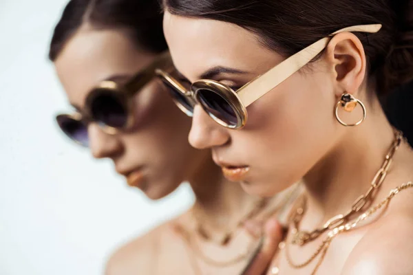 Giovane donna nuda in occhiali da sole, gioielli dorati vicino specchio con riflesso — Foto stock