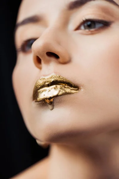 Close up de jovem com lábios pintados de ouro isolado em preto — Fotografia de Stock