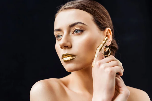 Молода гола жінка з золотим макіяжем і золотою фарбою на пальці ізольована на чорному — стокове фото