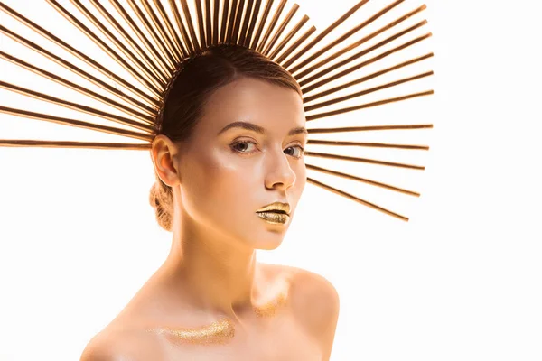 Joven mujer hermosa desnuda con maquillaje dorado y accesorio en la cabeza mirando a la cámara aislada en blanco - foto de stock