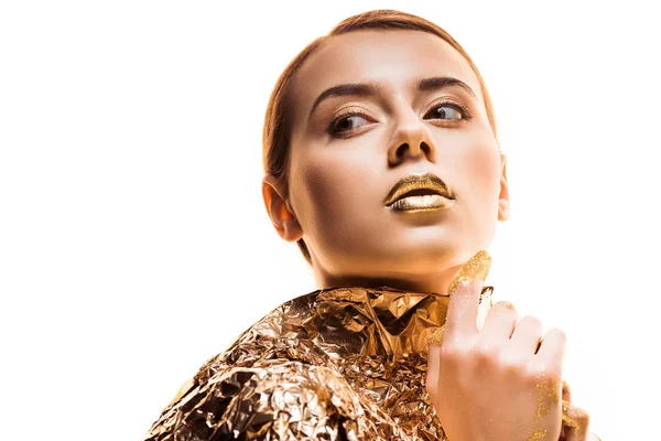 Young woman with golden lips in golden foil looking away isolated on white — Stock Photo