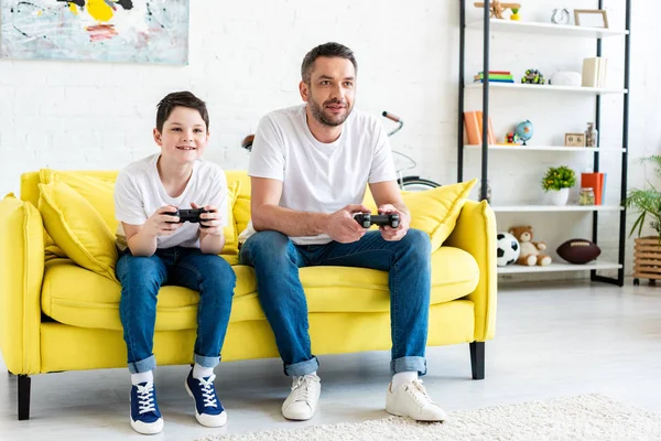 Pai e filho jogando Video Game no sofá na sala de estar — Fotografia de Stock