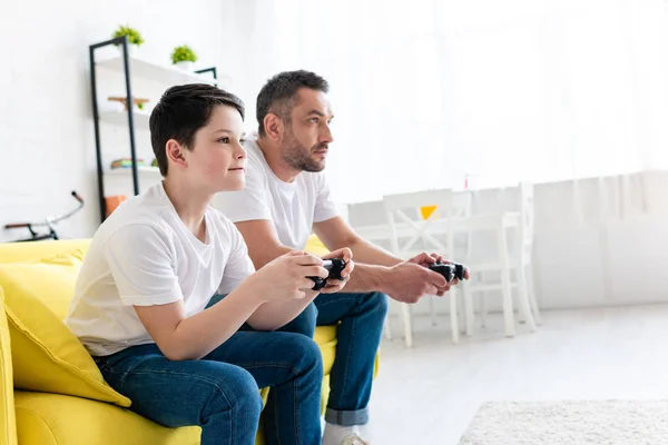 Pai e filho jogando Video Game no sofá na sala de estar com espaço de cópia — Fotografia de Stock