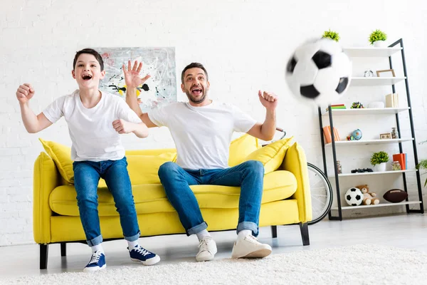Aufgeregter Vater und Sohn jubeln beim Anschauen eines Sportspiels im Wohnzimmer — Stockfoto