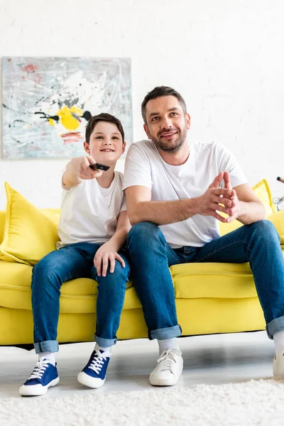 Pai e filho sentado no sofá e assistindo tv em casa — Fotografia de Stock