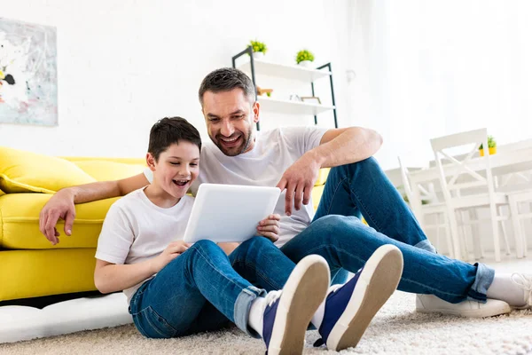 Pai e filho sentado no tapete e usando Digital Tablet na sala de estar — Fotografia de Stock