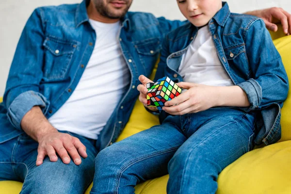 Abgeschnittene Ansicht von Vater und Sohn, die auf der Couch sitzen und zu Hause mit Spielzeugwürfel spielen — Stockfoto