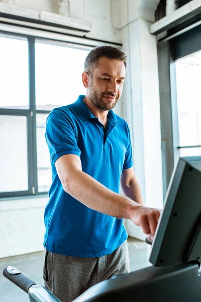 Handsome man working out on treadmill at gym — Stock Photo