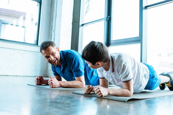 Father and son doing plank exercise on fitness mats at gym — Stock Photo